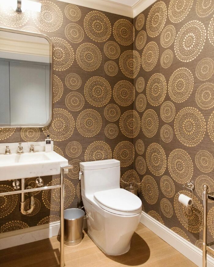 Bathroom with trendy brown circle-pattern wallpaper, white toilet, and sink showcasing stylish bathroom wallpaper ideas.