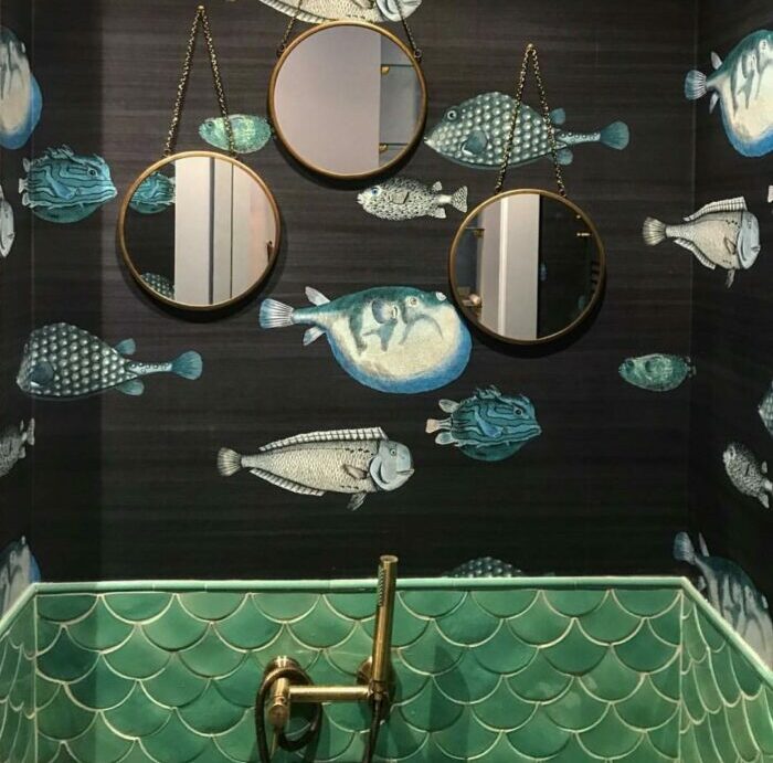 Bathroom wallpaper with fish designs, three hanging mirrors, and a water-themed sink creating a trendy space.