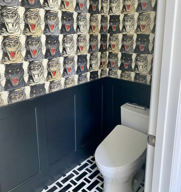 Bathroom featuring tiger pattern wallpaper and stylish black wainscoting, showcasing trendy bathroom wallpaper ideas.