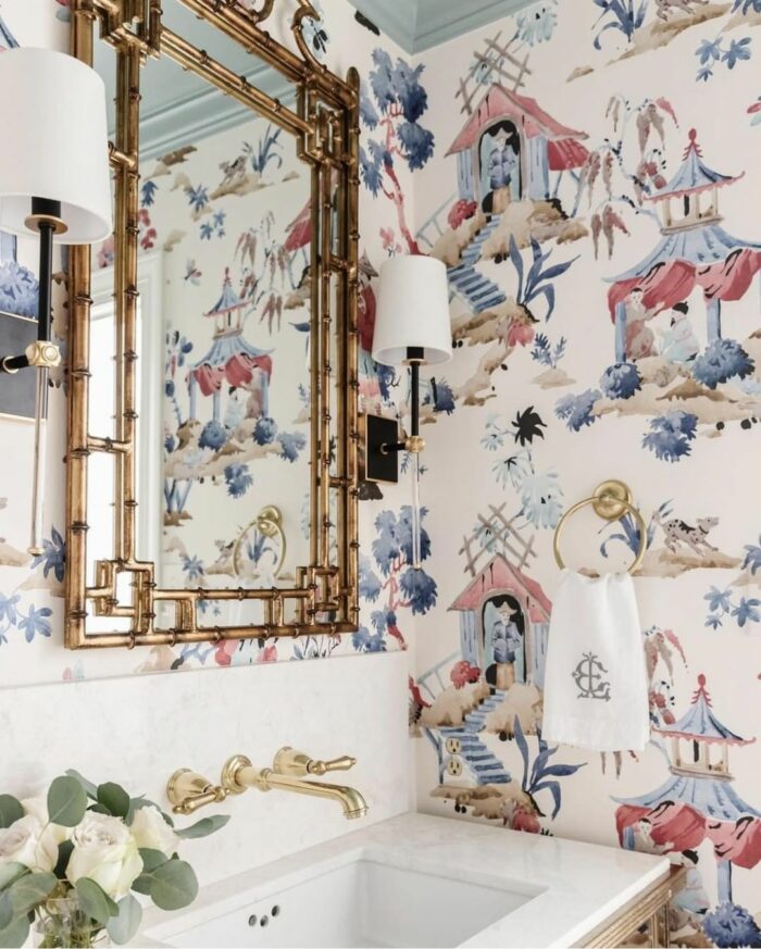 Bathroom with trendy chinoiserie wallpaper, gold fixtures, and a white sink showcasing stylish bathroom wallpaper ideas.