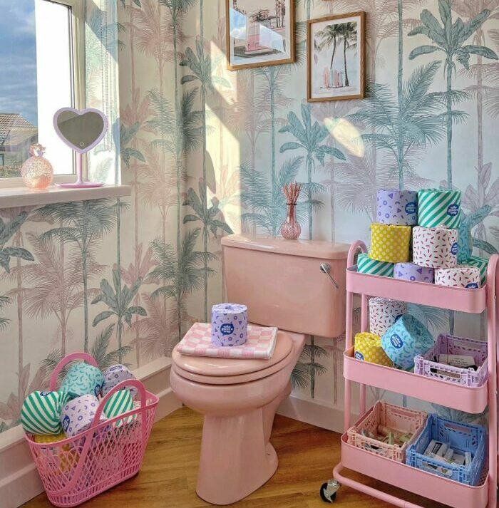 Pastel tropical bathroom wallpaper with a pink toilet and colorful decor creating a trendy bathroom wallpaper design.