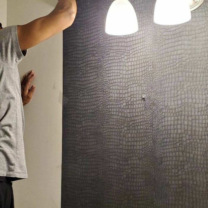 Black crocodile embossed wallpaper in bathroom under pendant lights showcasing trendy bathroom wallpaper ideas.