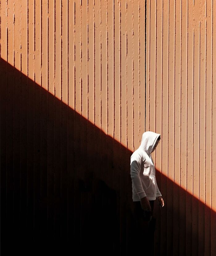 A photograph of a man with a hood on