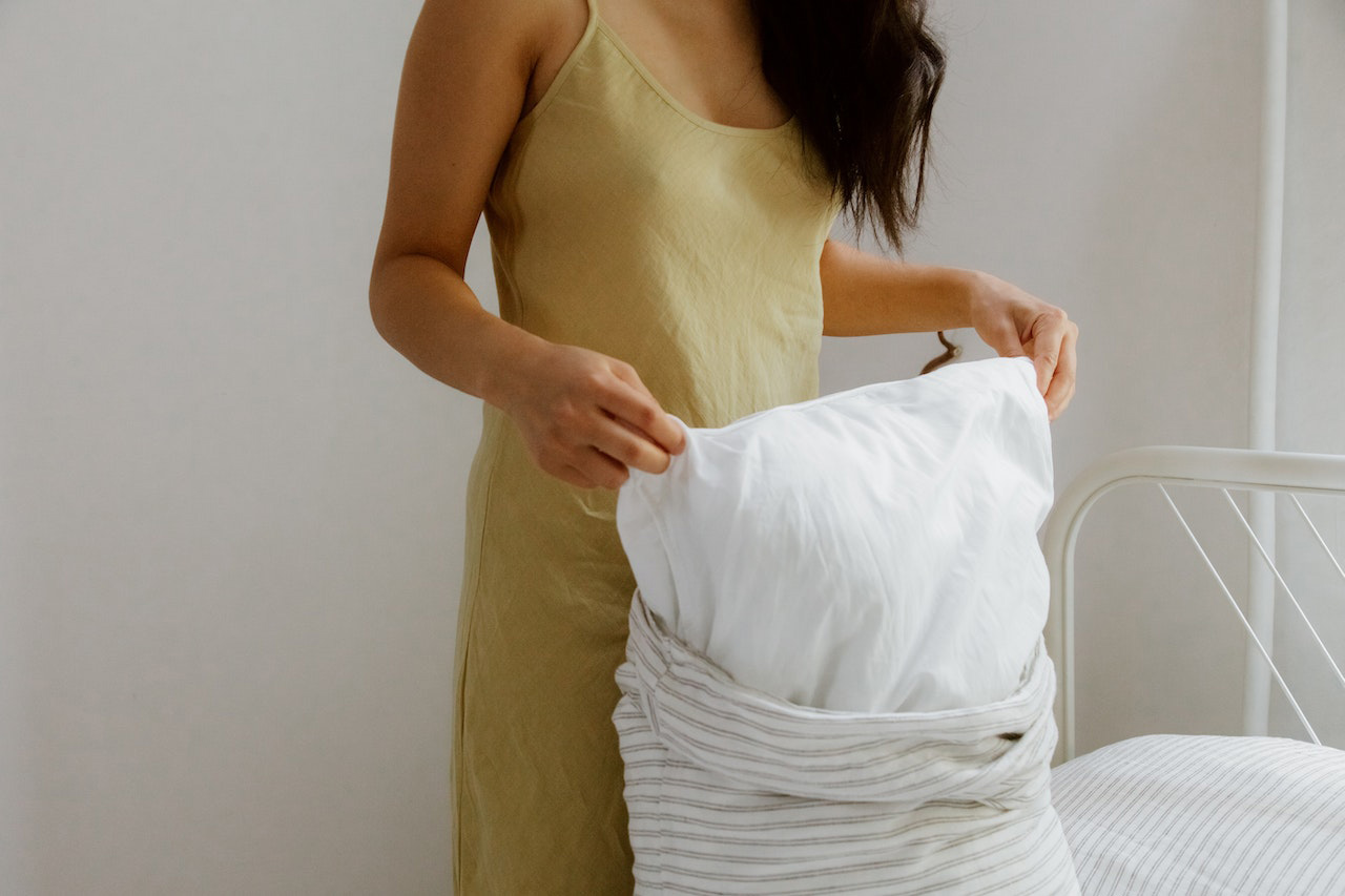 Woman with black hair changing light pillow case