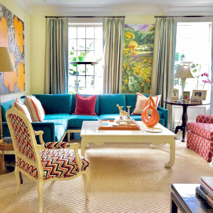 Blue banquette seating paired with patterned white chairs and a white table in a bright, cozy living room setting