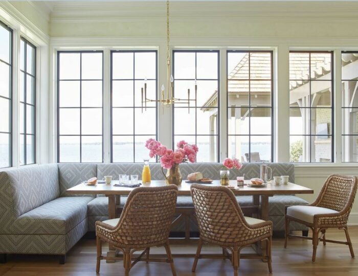 Patterned gray banquette seating paired with a wooden table and woven chairs in a bright dining area.