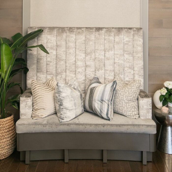 Gray banquette seating with decorative pillows, creating a cozy and stylish spot for enjoying flavorful delights.