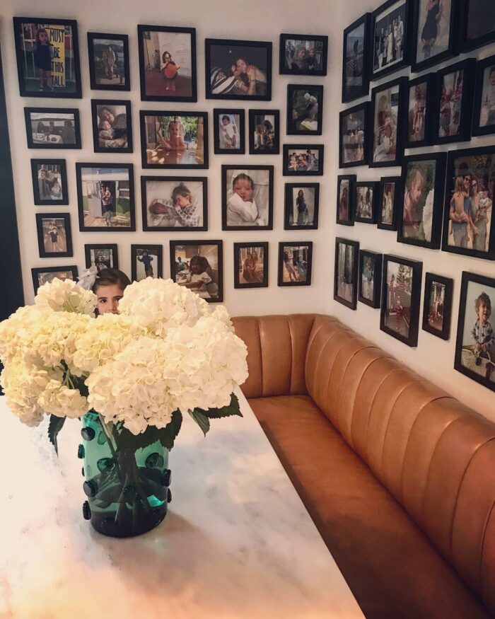 Brown leather banquette seating with white marble table and a wall filled with framed photo art in a cozy dining space