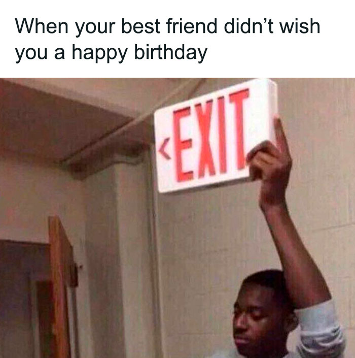 Man holding an exit sign with text about not receiving a happy birthday wish from a best friend.