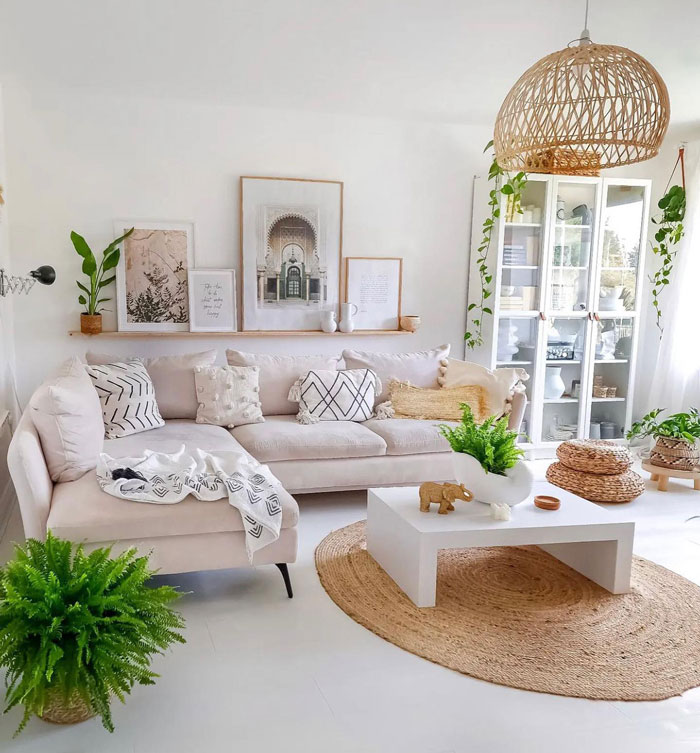Living room featuring beige couch with patterned pillows, boho decor elements, plants, and framed wall art for a chic space.