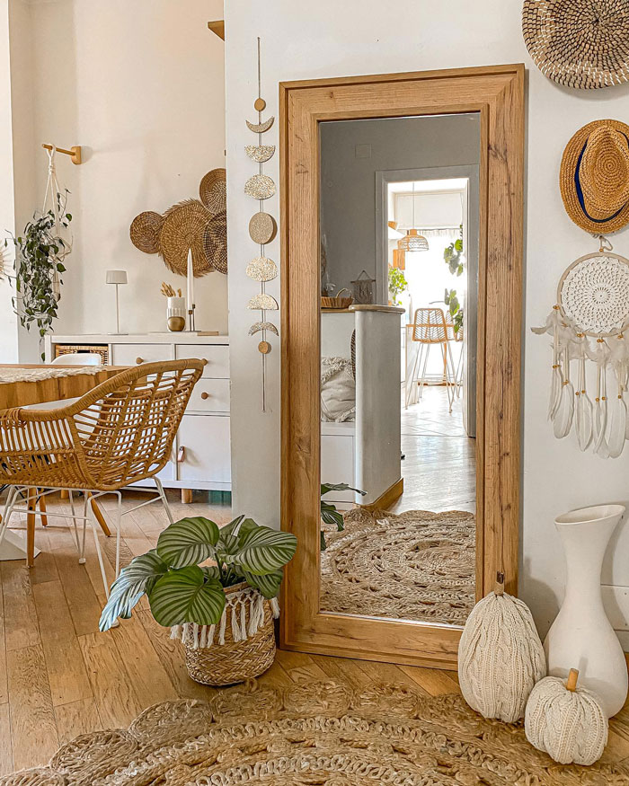Large wooden framed mirror on wall with boho decor plants and woven accents creating a chic boho decor space.