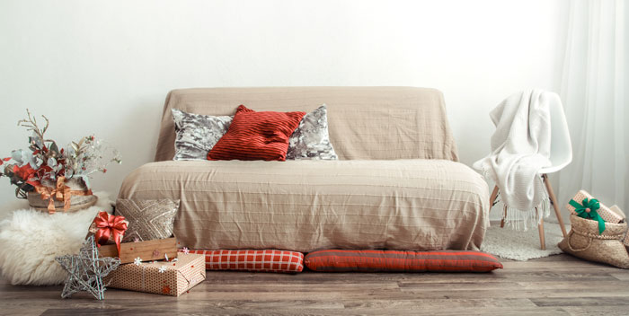 Beige couch with red and silver pillows, surrounded by wrapped Christmas presents for unique boho decor ideas.