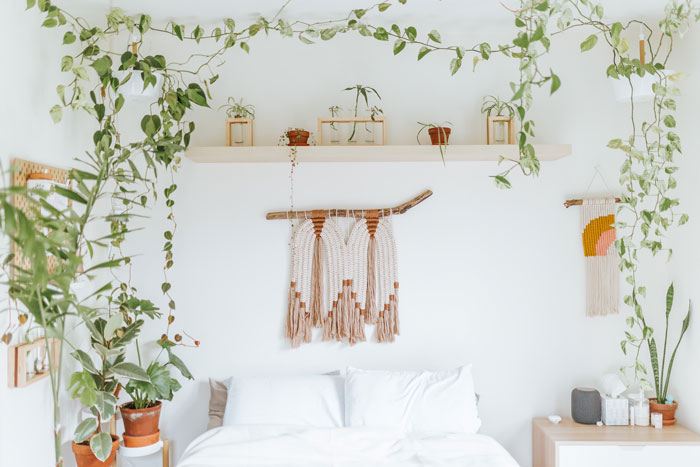 Boho decor bedroom filled with hanging and potted plants, macrame wall art, and natural light for a chic space.