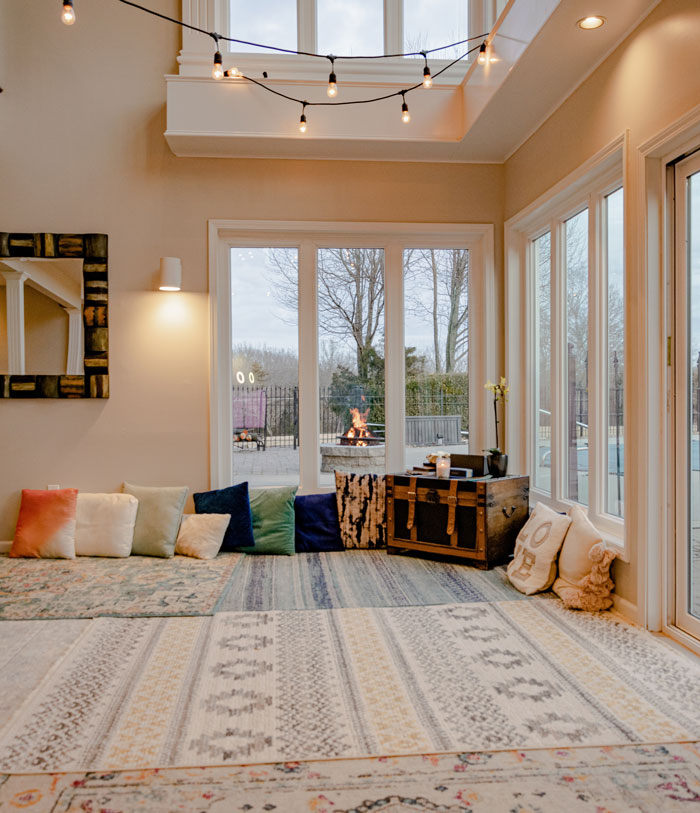Cozy boho decor with a pile of colorful pillows near window and hanging string lights creating a chic space ambiance