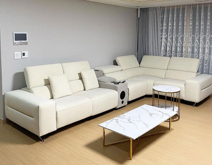 Large white cheap couch with USB ports and cup holders in modern living room with marble coffee tables. Large white cheap couch with USB ports and cup holders in modern living room with marble coffee tables.