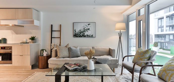 Light gray microfiber cheap couch with two large throw pillows in a bright modern living room setting Light gray microfiber cheap couch with two large throw pillows in a bright modern living room setting