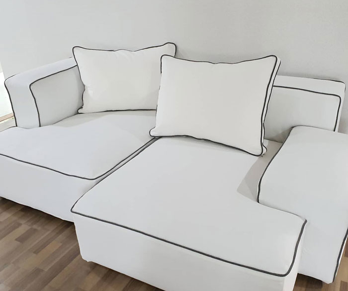 White couch slipcover with black edges on a budget-friendly cheap couch in a modern living room setting White couch slipcover with black edges on a budget-friendly cheap couch in a modern living room setting