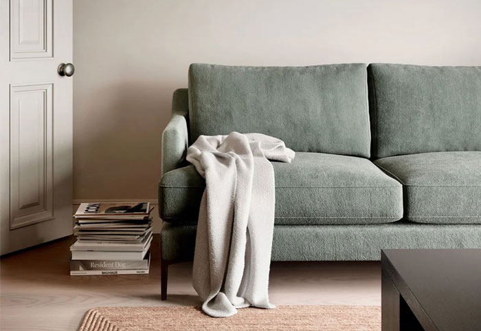 Simple gray two seater sofa with a blanket draped over armrest, showcasing a budget-friendly cheap couch option. Simple gray two seater sofa with a blanket draped over armrest, showcasing a budget-friendly cheap couch option.