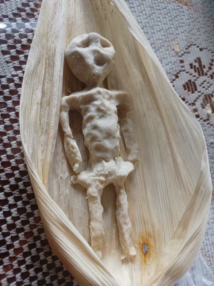 Cursed food resembling an alien figure made from dough on a corn husk.