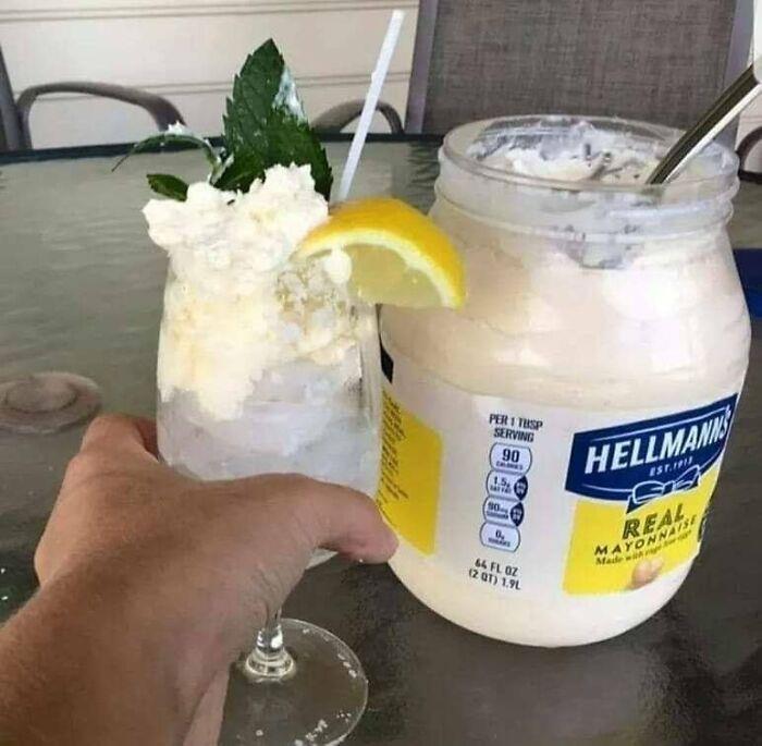 Cursed food creation featuring a cocktail with mayo, mint, and lemon garnish next to a jar of mayonnaise.