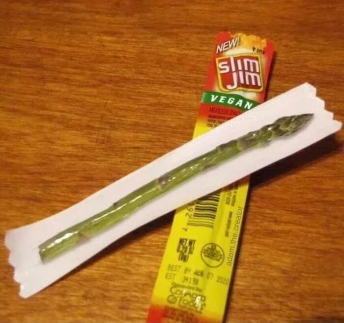 Cursed food: A single asparagus stick packaged like a Slim Jim, sitting on a wooden surface.