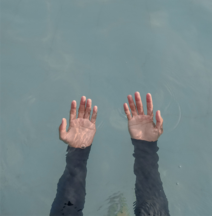 Hands reaching out from water with eerie lighting, illustrating scary facts that create a chilling and unsettling feeling.