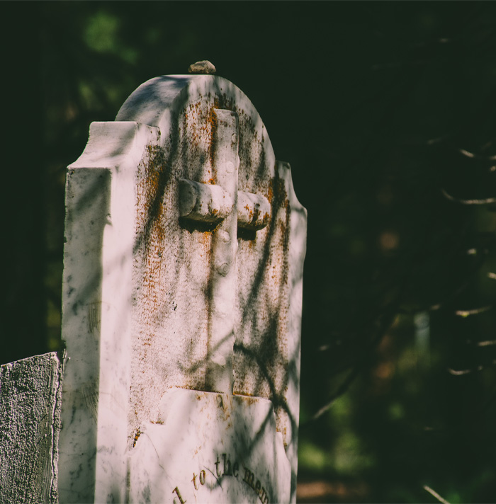 Weathered old gravestone with a cross in a dark, eerie cemetery setting evoking scary facts and creepy vibes
