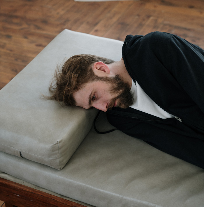 A pensive man lying on a couch, appearing unsettled, capturing the vibe of scary facts that give heebie-jeebies.
