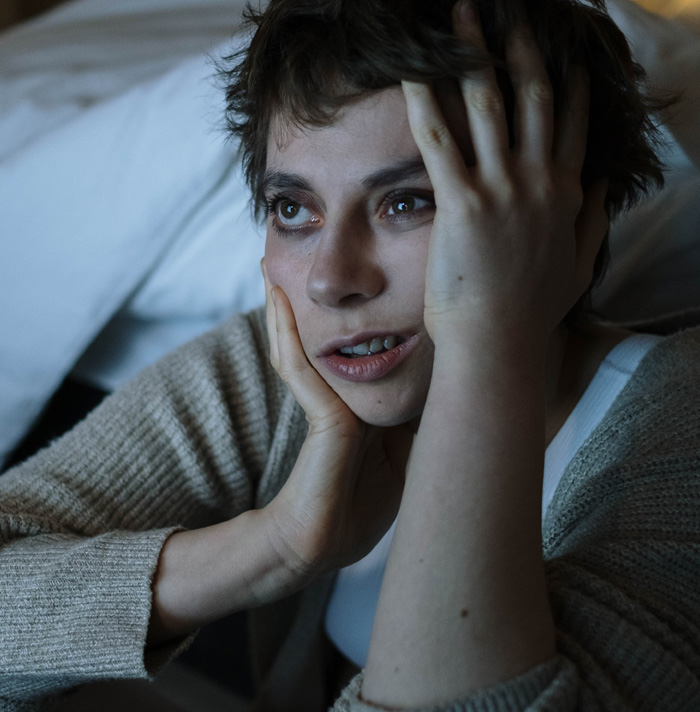 Person with worried expression holding face, reflecting fear and anxiety related to scary facts and heebie-jeebies.