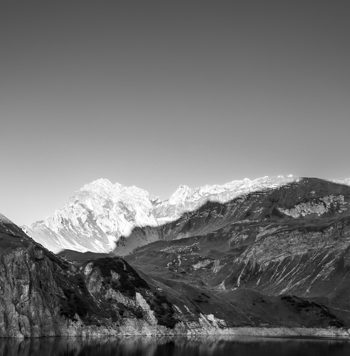 Black and white mountain landscape with rugged rocks and lake, evoking a sense of scary facts and spooky atmosphere.