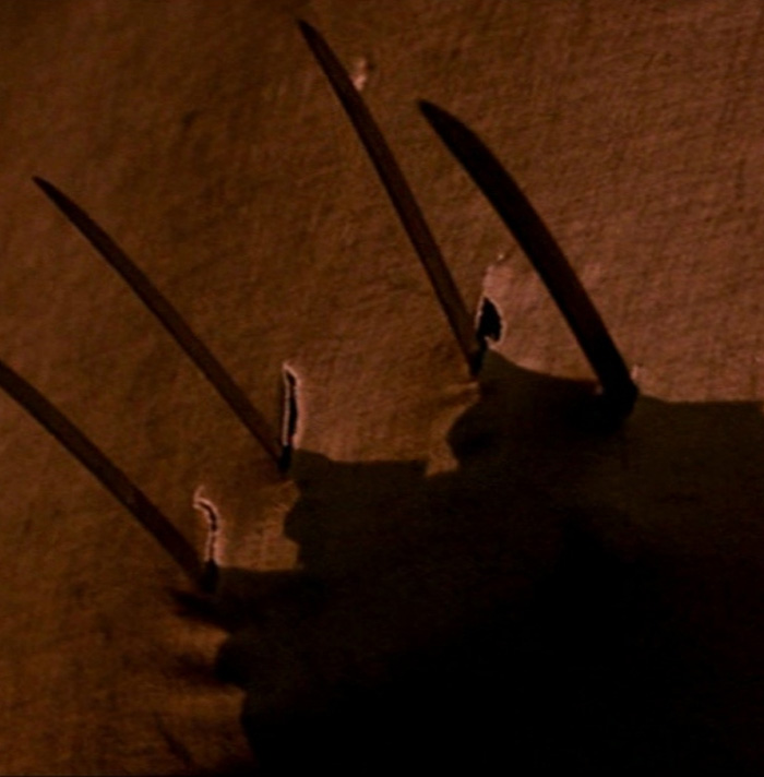 Shadow of a hand with long sharp blades casting eerie shapes on a textured surface for scary facts theme.