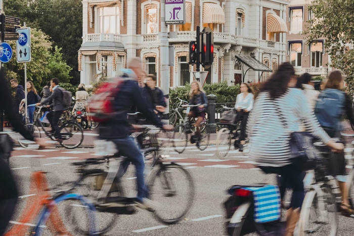 People riding bicycles on busy Amsterdam street showcasing culture diversity and beauty of the world during daytime.