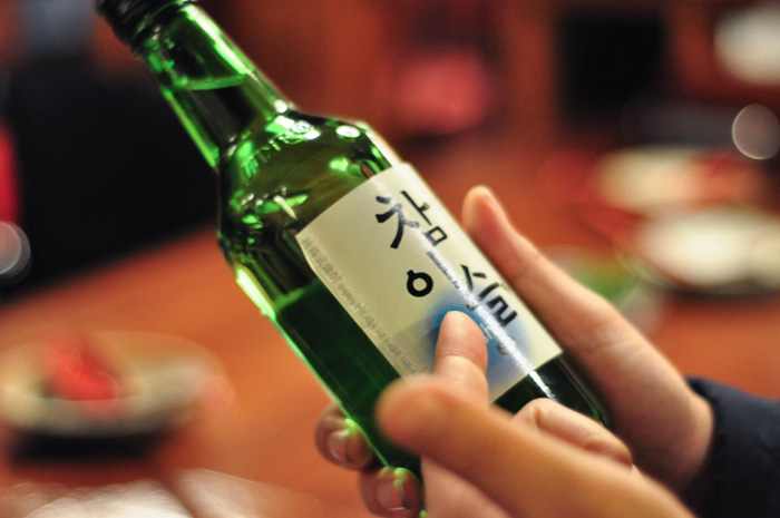 Person holding a bottle of Soju, representing culture facts reflecting the diversity and beauty of the world.