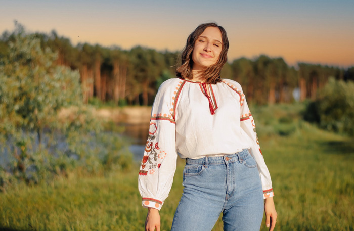 A woman wearing a traditional Vyshyvanka blouse, smiling outdoors, reflecting cultural diversity and beauty of the world.
