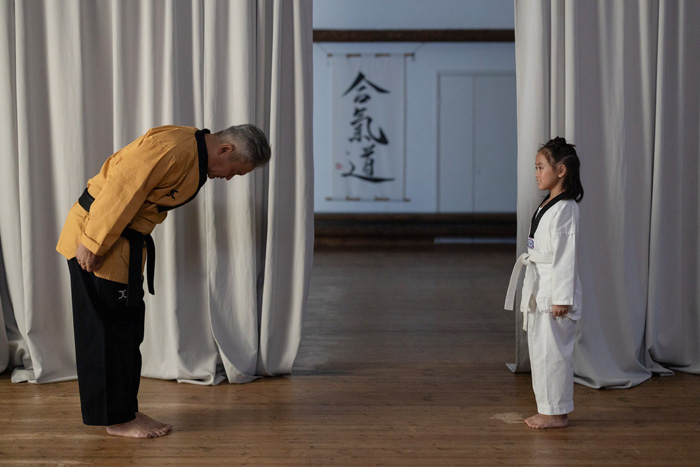 Martial arts instructor bowing to a young student, showcasing cultural tradition and diversity in the world.