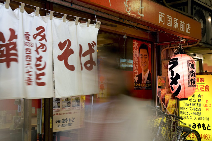 Ramen restaurant entrance in Tokyo with traditional red and white noren, showcasing cultural diversity and beauty of the world.