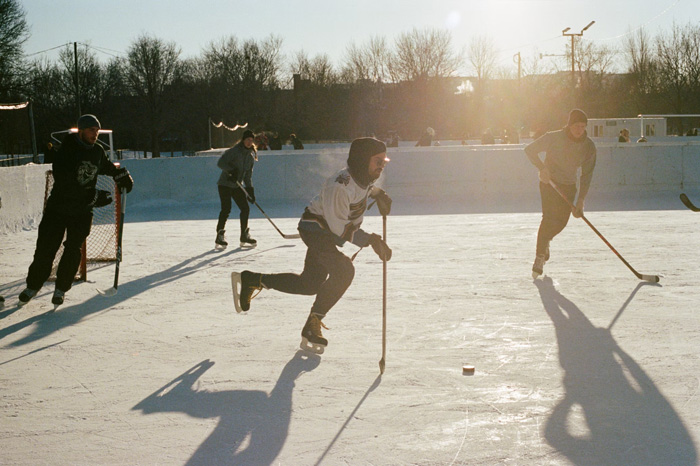 Group of people playing outdoor hockey in Montréal, reflecting culture diversity and the beauty of winter sports.
