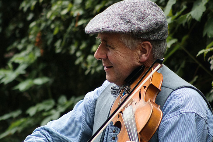 An old man playing a violin in Bunratty, County Clare, Ireland, showcasing culture facts reflecting diversity and beauty.