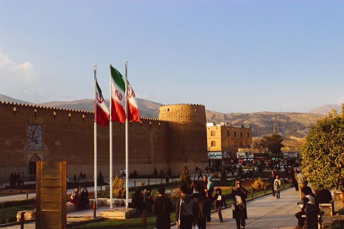 People walking near Karim Khan Citadel in Iran at sunset, showcasing culture and diversity of the world.