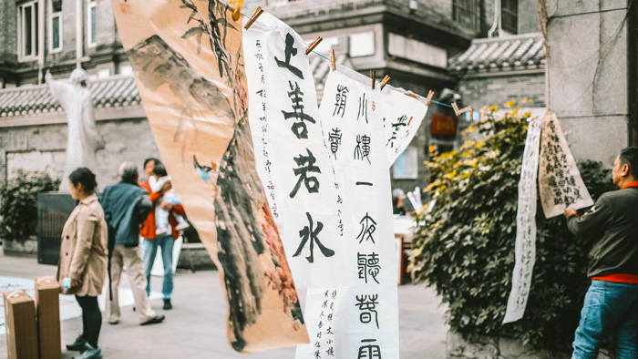 Hanging sheets of paper with calligraphy text displayed outdoors representing culture facts and diversity of the world.