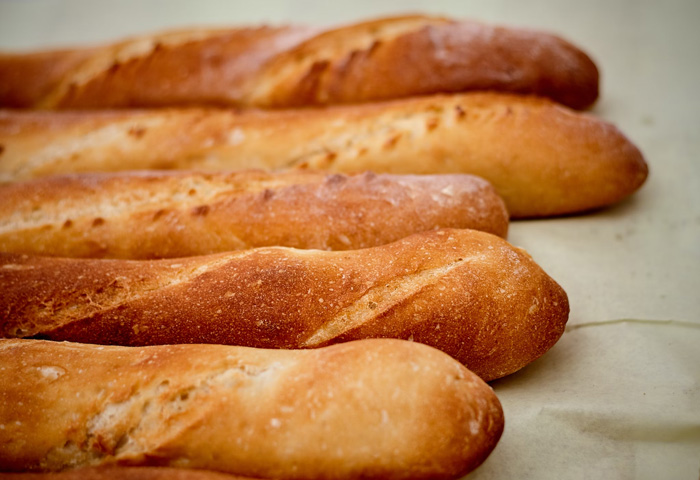 Several freshly baked baguettes on a flat surface, showcasing cultural diversity and beauty of the world.