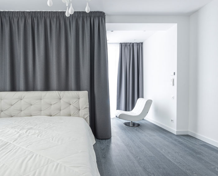 a cozy white bed near the grey curtains 