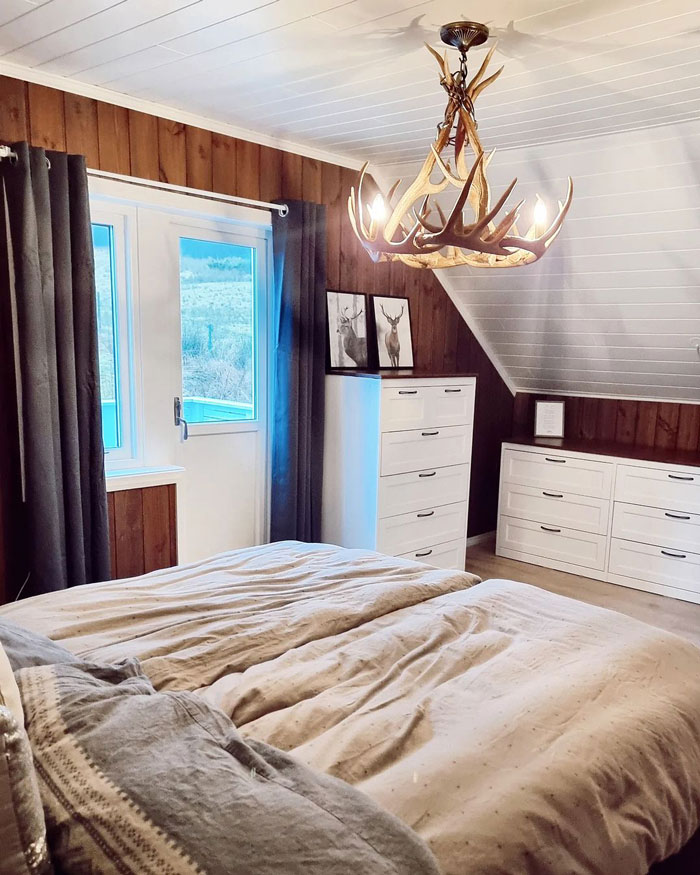 chandelier with antler over the bed and dark gray curtains on the balcony window
