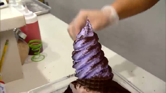Person wearing gloves preparing a purple soft serve ice cream cone, revealing disturbing behind-the-scenes secrets about popular meals.