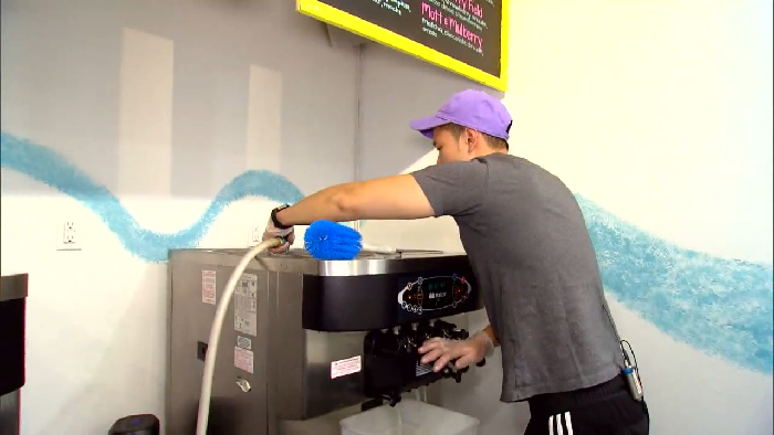 Worker cleaning a soft serve ice cream machine revealing disturbing behind-the-scenes secrets of popular meals.