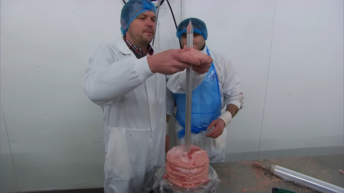 Food industry workers in protective gear handling raw meat, revealing disturbing behind-the-scenes secrets about popular meals.