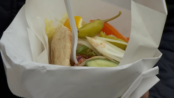 Close-up of a popular meal wrapped in paper showing fresh vegetables and pita bread, revealing disturbing behind-the-scenes secrets.