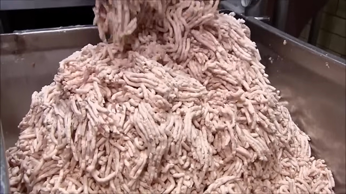 Large pile of raw ground meat being processed, revealing disturbing behind-the-scenes secrets about popular meals worldwide.