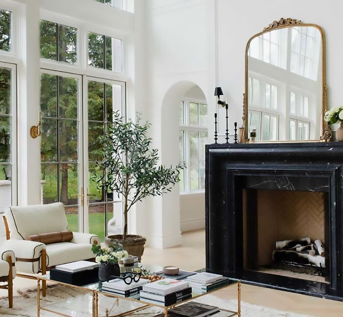 Modern living room featuring a sleek black marble fireplace mantel with elegant decorative accents and natural light.