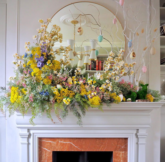 White fireplace mantel with red marble detailing decorated with bright colorful flowers and Easter ornaments